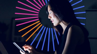 Woman using mobile device with digital graphics behind her